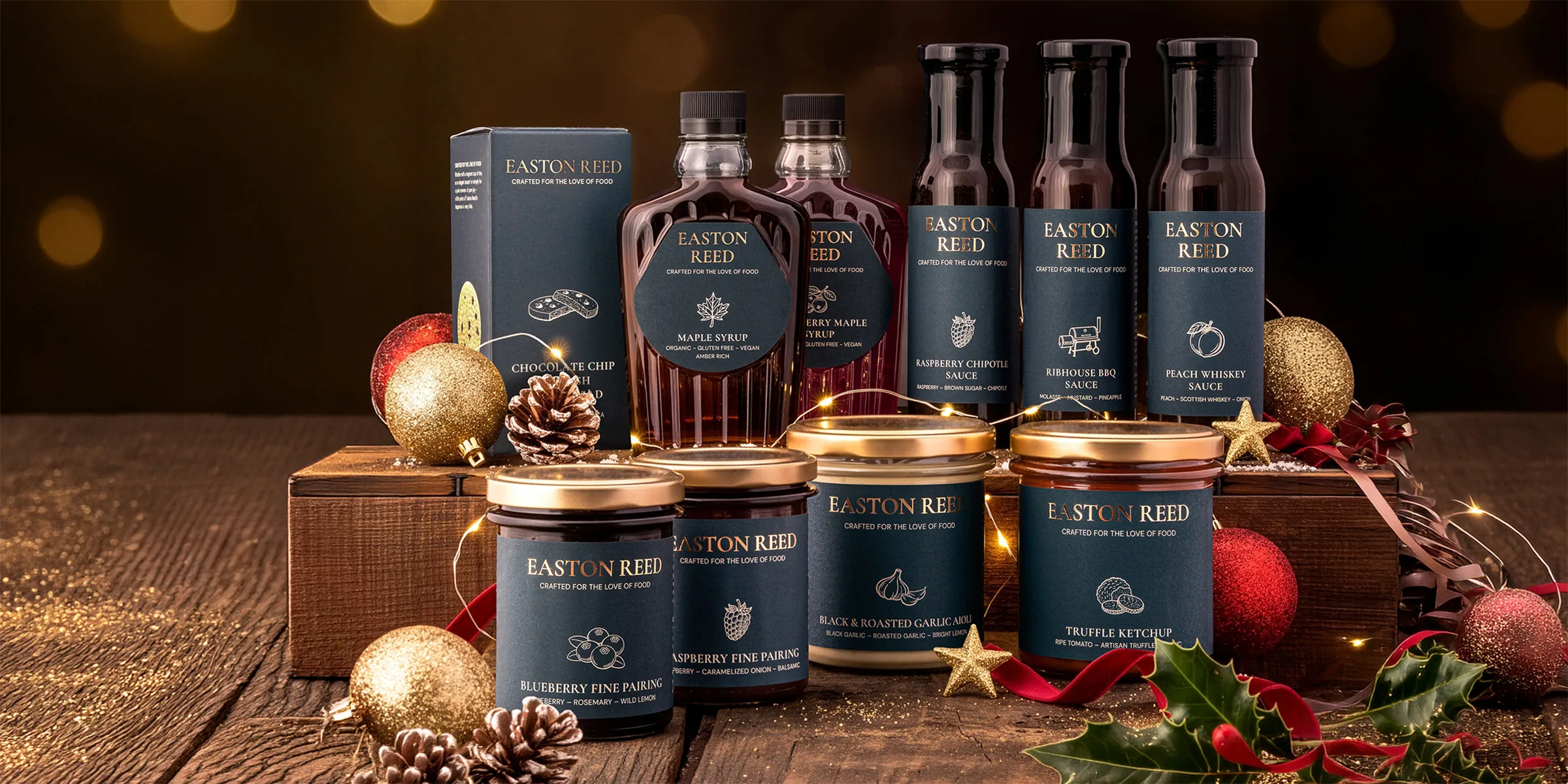 Easton Reed sauces, maple syrup, Fine Pairings and gift box on dark wood in front of golden Christmas lights